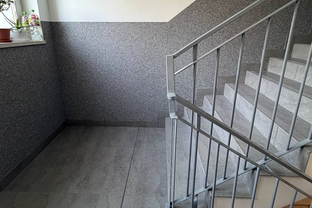 Szara lamperia mozaikowa i odnowiona balustrada przy biegu schodów